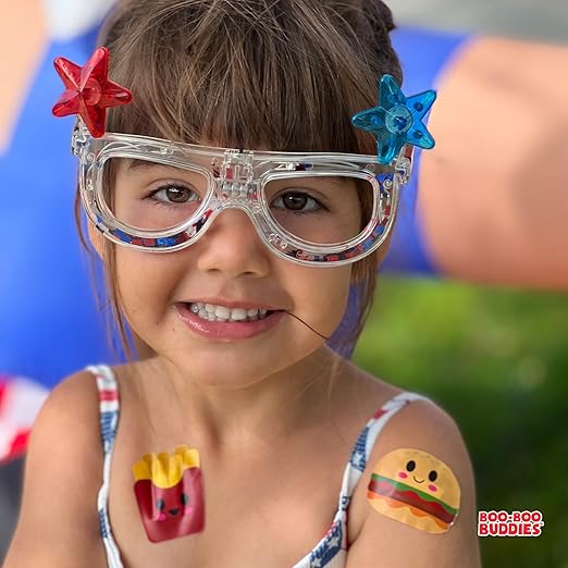 Smiling child wearing Boo Boo Buddies fun and colorful kids bandages on arms during outdoor play.