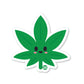 A die-cut vinyl sticker of a cute cannabis leaf with a smiling face on it.