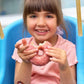 Smiling child eating a snack while wearing Boo Boo Buddies fun and colorful kids bandages on her arms.