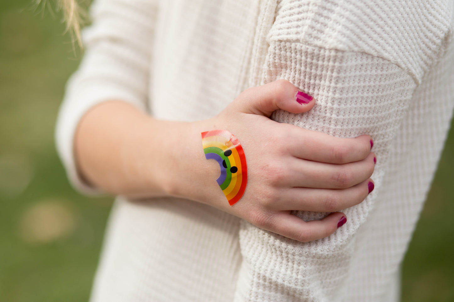 Closeup of Boo Boo Buddies rainbow bandage on hand, bright cheerful bandaid for kids that adds color and comfort to minor scrapes.
