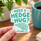 Hand holding a 3-inch Need a Hedge Hug mint-green hedgehog sticker.